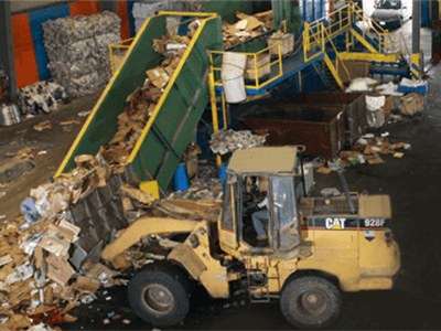 Tractor unloading dumpster at facility